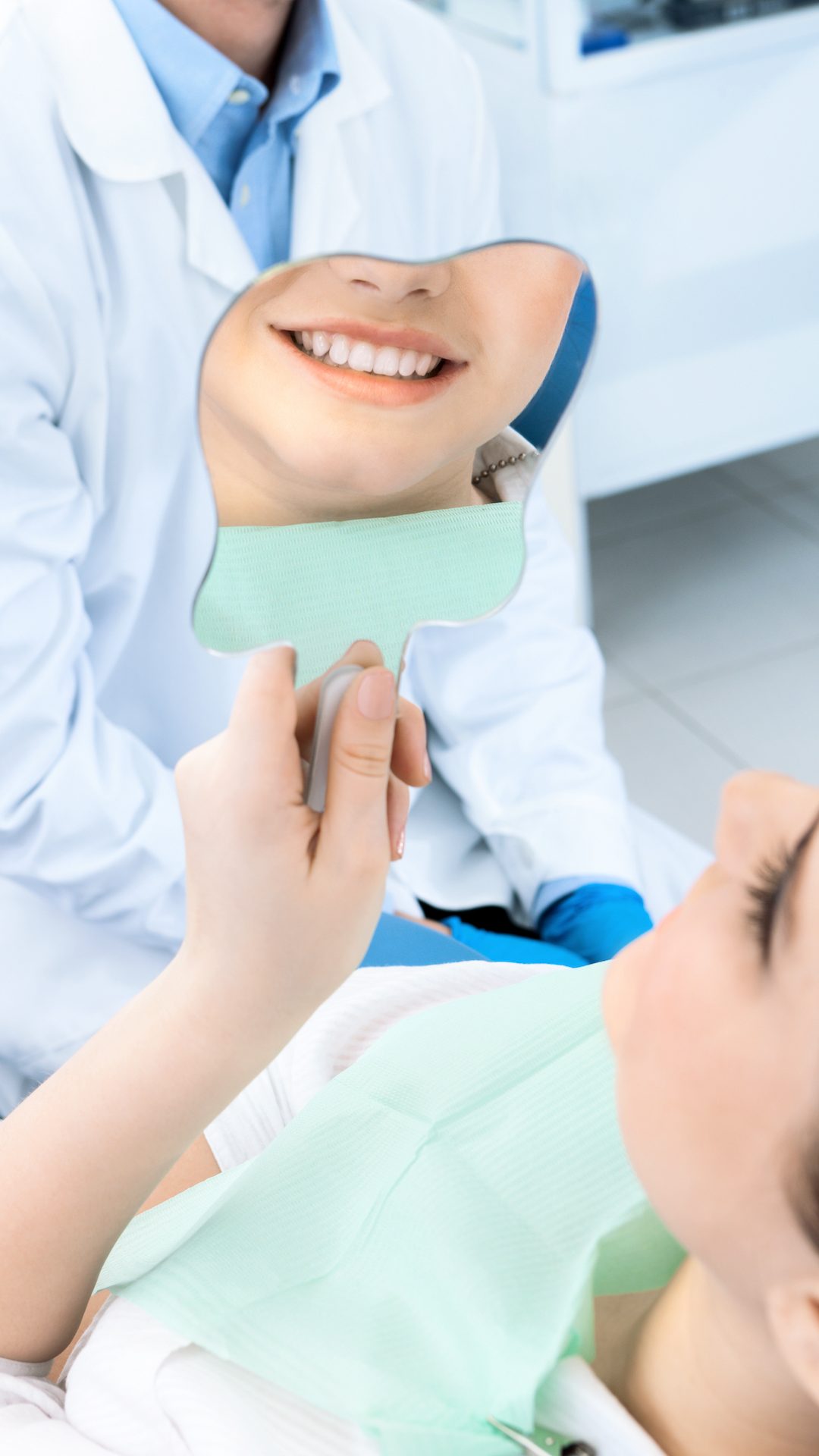 The patient admires her smile looking at the mirror after the treatment